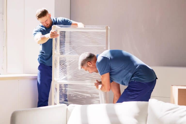 Two movers arranging assembly furniture in a new home
